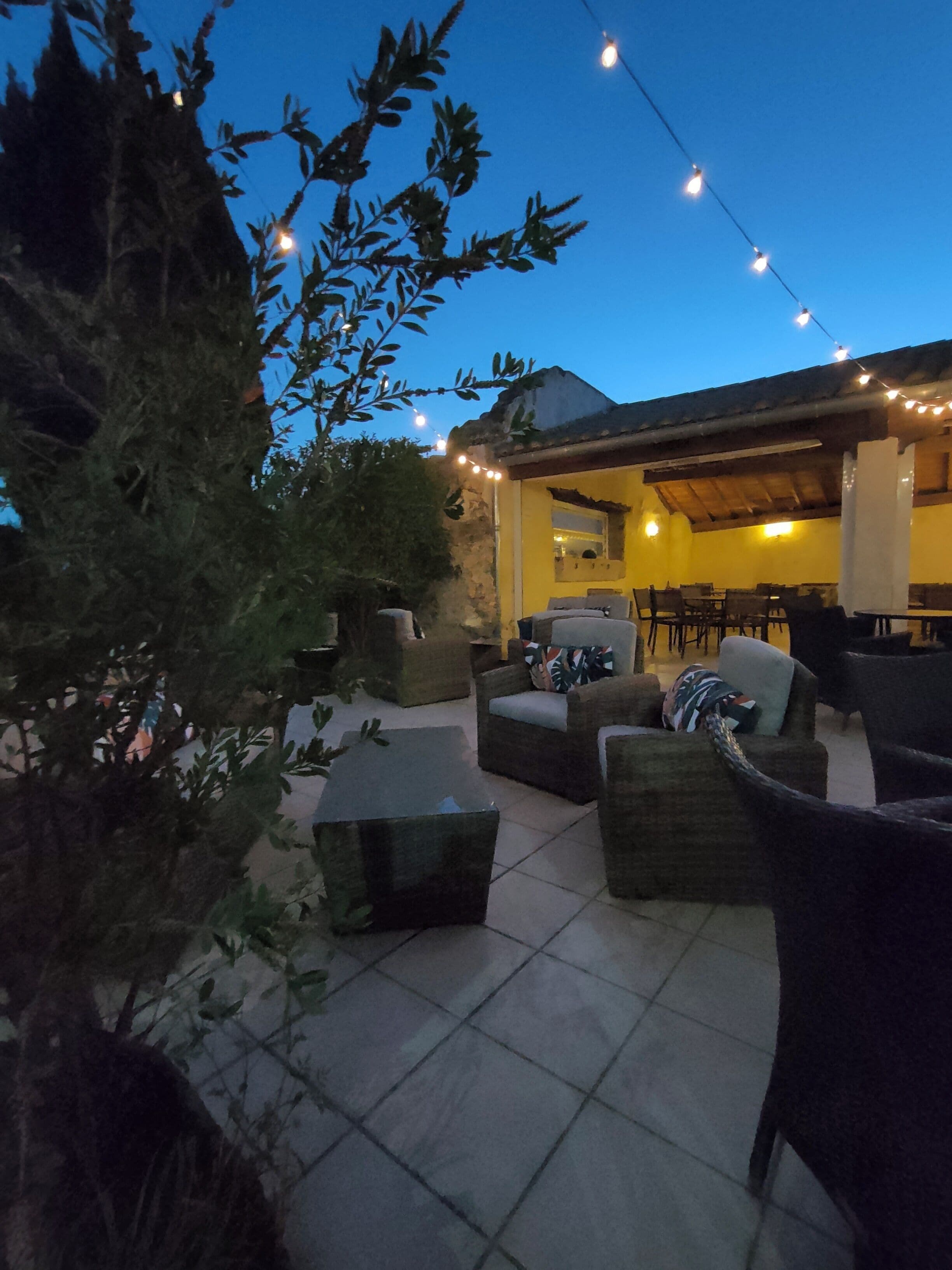 An outdoor patio area with seating arrangements and string lights.