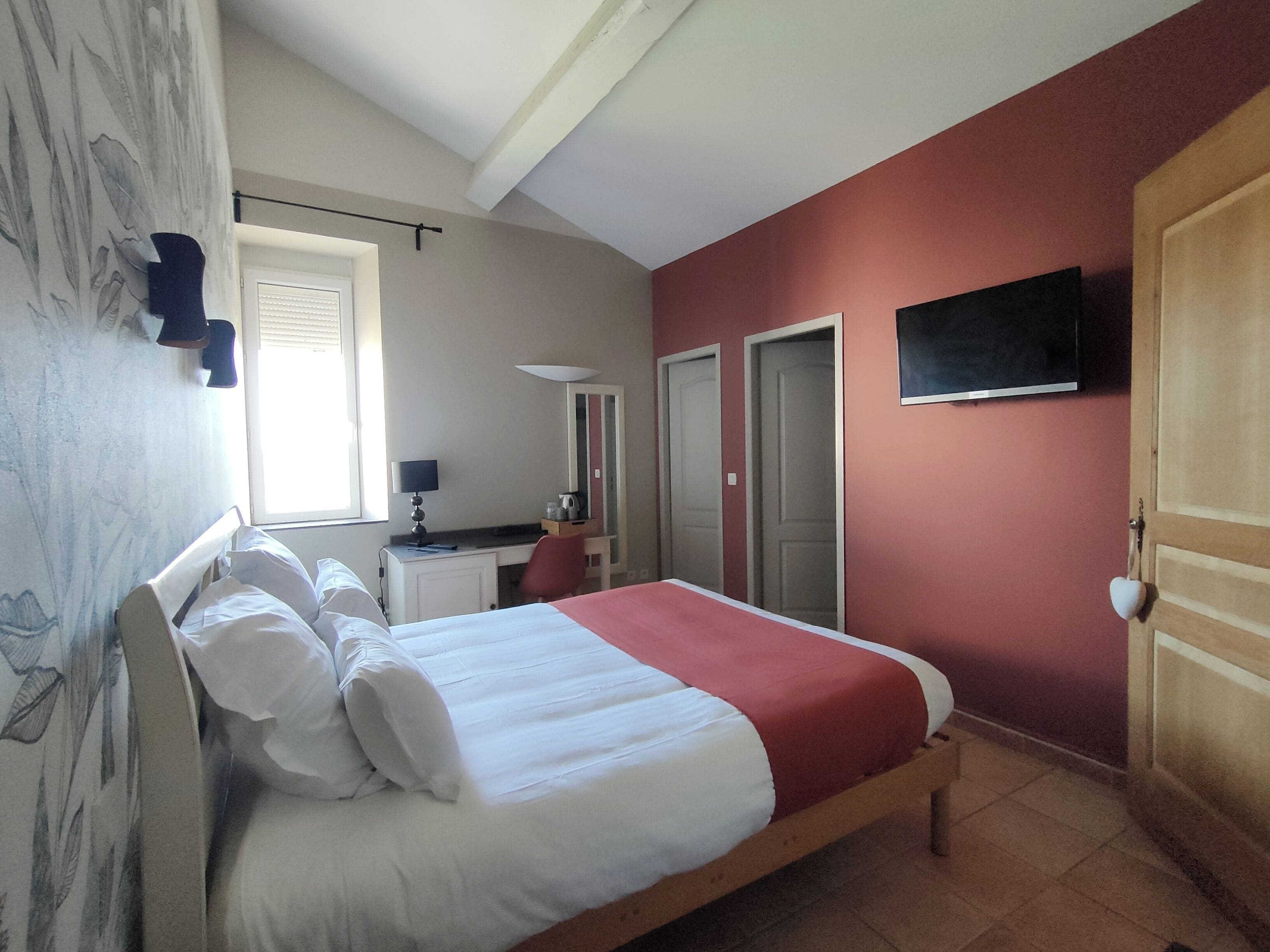 Camera da letto con un letto, una scrivania, una sedia, una TV e due porte.