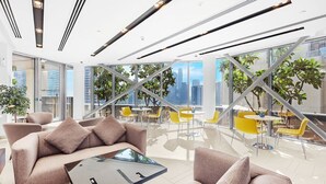 Een modern interieur met een bank, salontafel, gele stoelen en uitzicht op de stad door grote ramen.