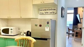 A kitchen with a stainless steel refrigerator, a microwave, and a sign above the refrigerator that reads "COME GATHER IN OUR KITCHEN." - Beau Vallon Studios (Mahé Island)