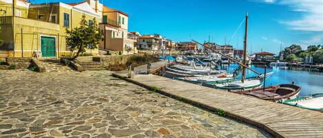 A stone-paved waterfront with boats docked and buildings along the shore.