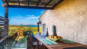 Eine Terrasse im Freien mit Tisch für zwei Personen, einer Flasche und einer Obstschale.