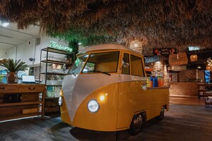 A vintage car-shaped bar area with a rustic ceiling and a neon sign in the background.