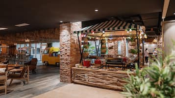 A cozy restaurant with a rustic stone wall, wooden furniture, and a thatched ceiling.