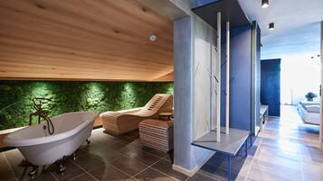 Ein modernes Badezimmer mit einer freistehenden Badewanne, einer Holzbalkendecke und einer grünen Wand.