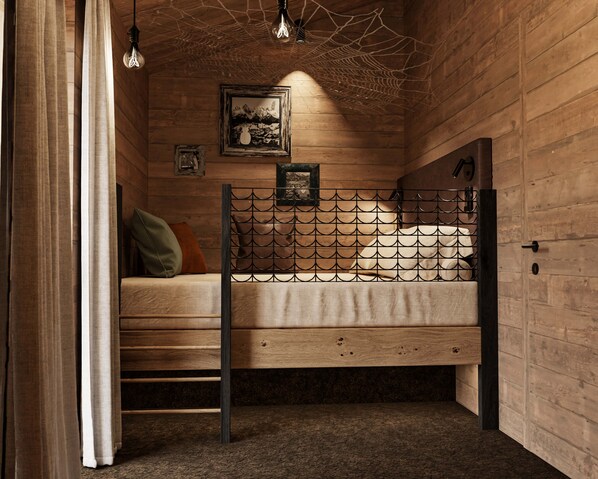 Une pièce en bois avec un lit superposé, un tableau encadré au mur et un luminaire suspendu.