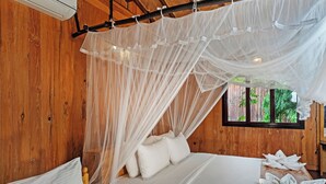 Quarto de madeira com cama sob um dossel, uma janela e uma pequena mesa com toalhas.