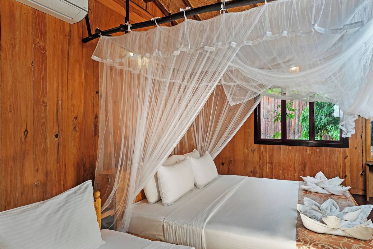 Une pièce en bois avec un lit sous un dais, une fenêtre et une petite table avec des serviettes.