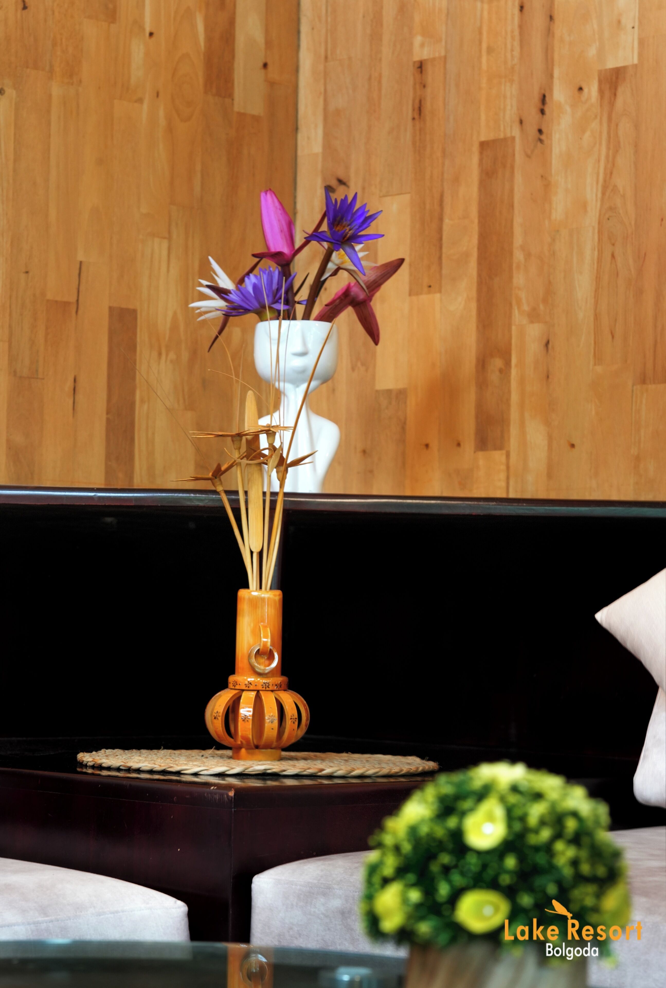 A wooden wall, a white bust sculpture, and a vase with flowers.