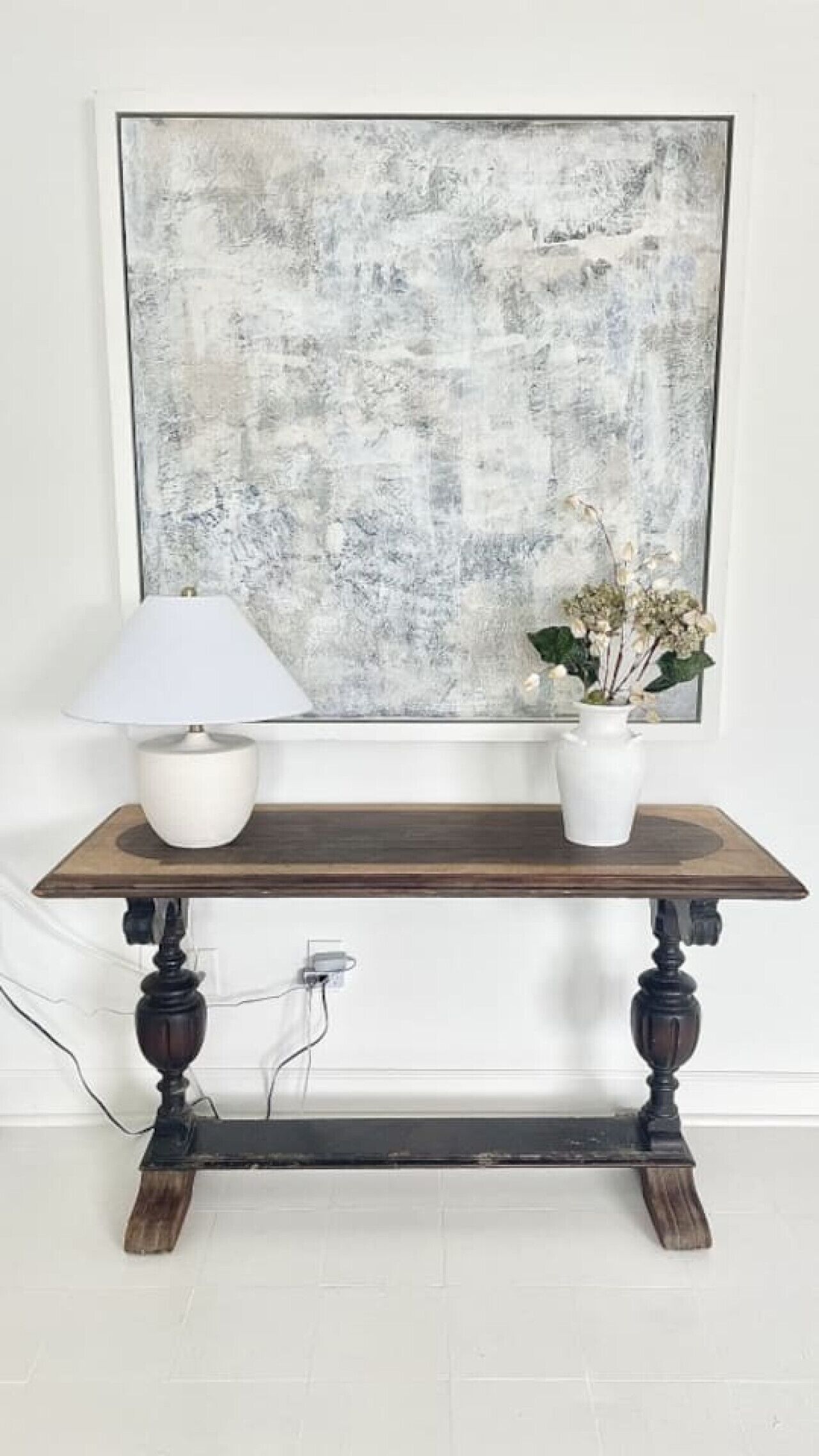 A wooden console table with a white lamp and a potted plant.