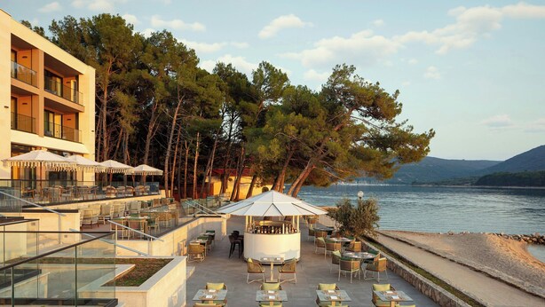An outdoor terrace with tables and chairs, a bar area, and a view of the sea. - The Isolano, Cres, Autograph Collection (Cres)