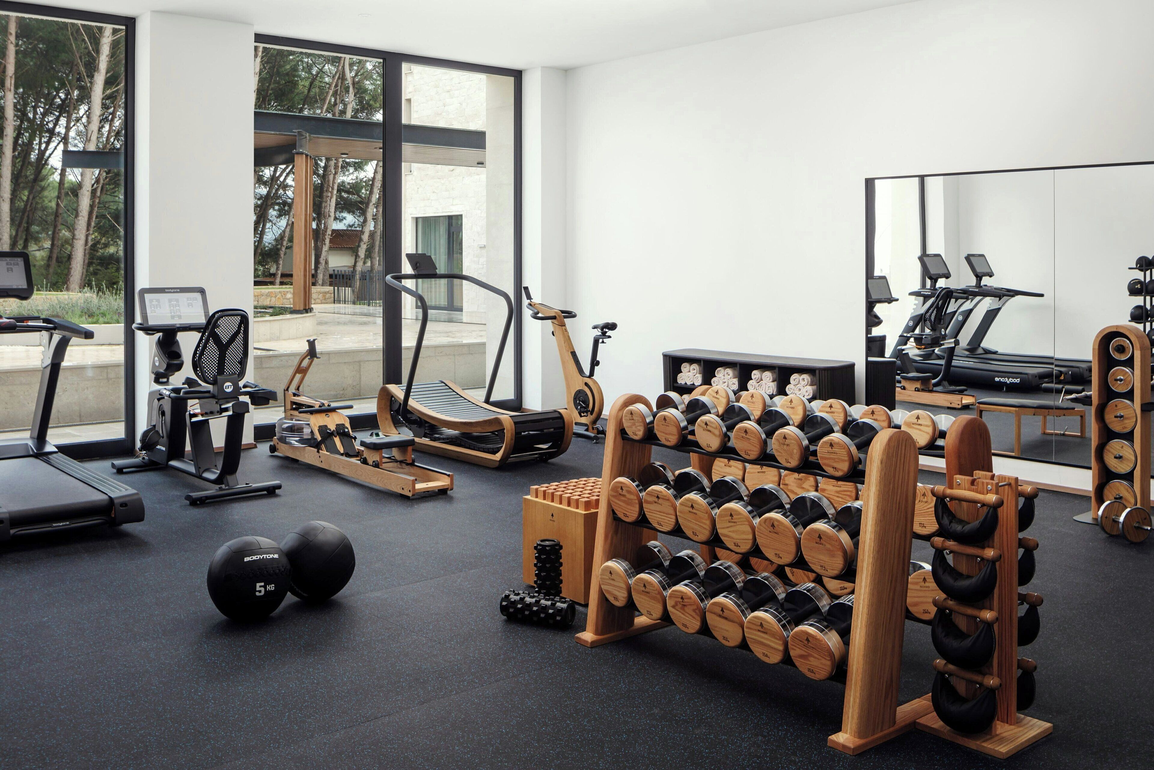 Ein modernes Fitnessstudio mit Trainingsgeräten, Laufband und einer Spiegelwand.