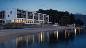 A modern hotel with multiple floors, balconies, and a waterfront view. - The Isolano, Cres, Autograph Collection (Cres)