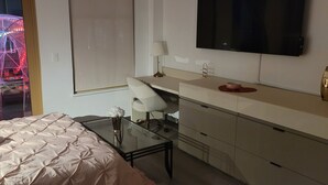 Hotellihuone, jossa on sänky, työpöytä, televisio ja näköala huvipuiston pyörälaitteelle.