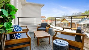 A balcony with wooden furniture, a potted plant, and a view of neighboring buildings. - 2 Luxury Houses w/ Patios | 1 Block from King St (Charleston)