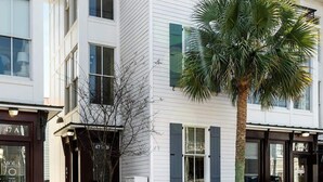 A white building with a corner entrance and a palm tree in front. - 3 Luxury Houses w/ Patios | 1 Block from King St (Charleston)