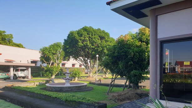 A courtyard with a central fountain, surrounded by trees and a paved walkway. - Mayon View Garden Apartelle Sa Bukid (Legazpi)