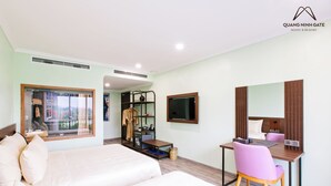 Una habitación de hotel con cama, escritorio, silla, televisor y armario.