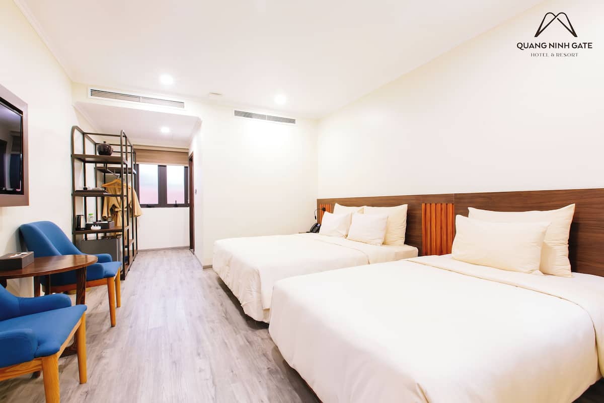 Une chambre d ’hôtel avec deux lits, un bureau avec une chaise et un petit coin salon.