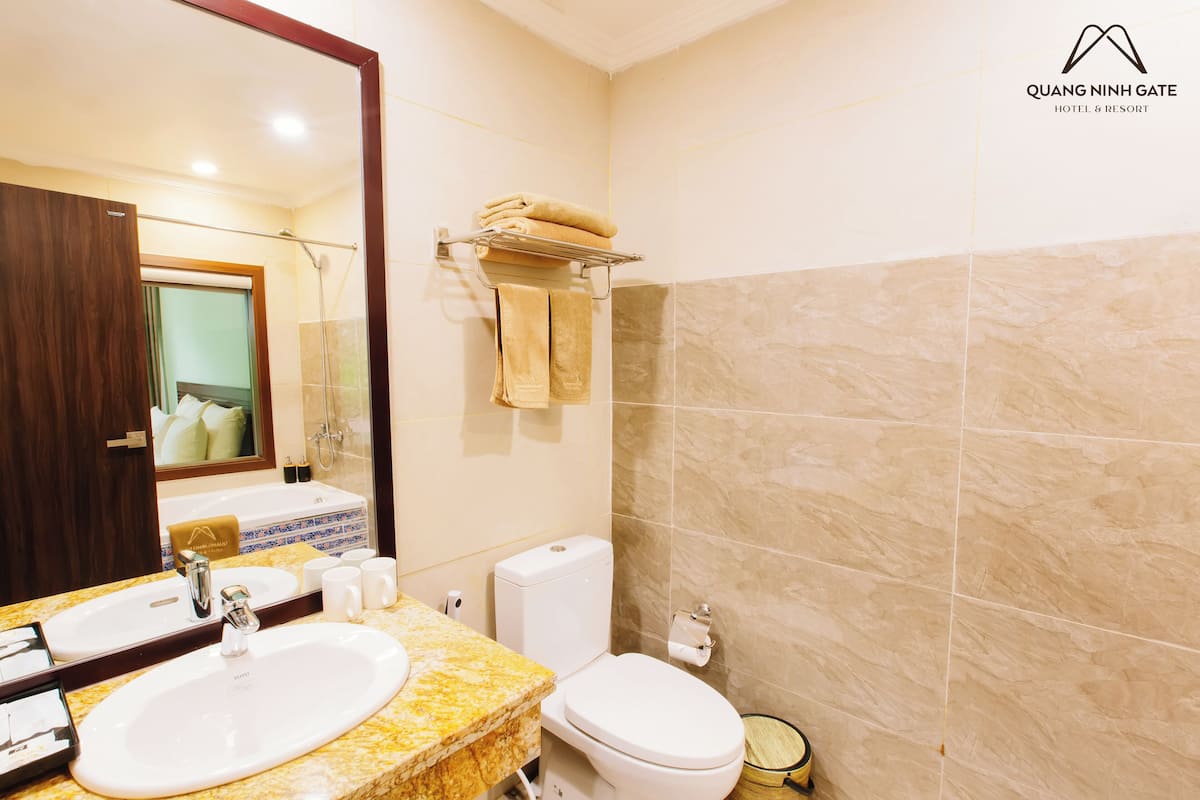 Une salle de bain avec un grand miroir, deux lavabos, des toilettes et un porte-serviettes.