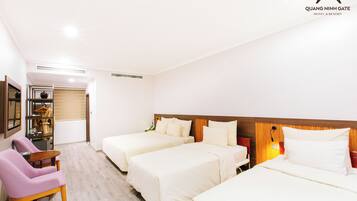 A hotel room with three beds, a desk, a chair, and a wardrobe.