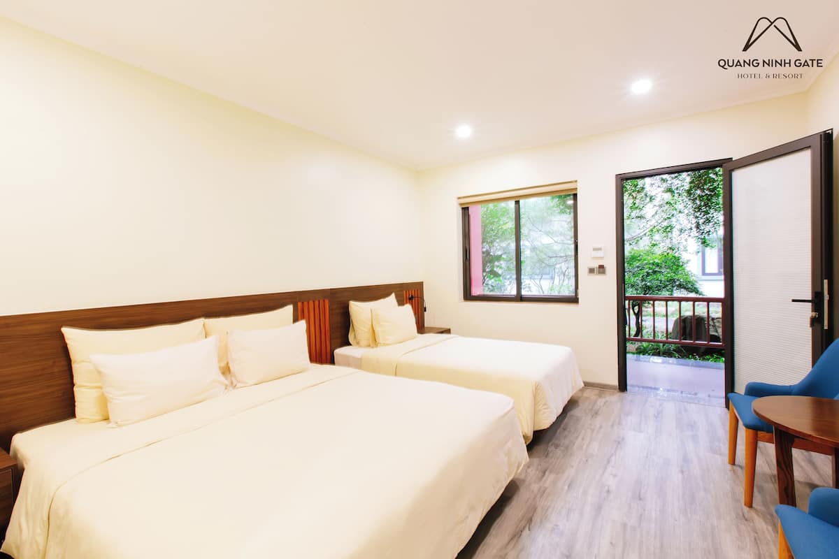 Une chambre d’hôtel avec deux lits, une tête de lit en bois, une fenêtre et une vue sur la verdure.