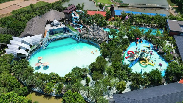 Vista aérea de un parque acuático con varias piscinas, toboganes y un puente que conecta diferentes zonas.