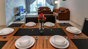 Een eethoek met een tafel voor vier personen, een vaas met bloemen en een uitzicht op de stad door grote ramen.