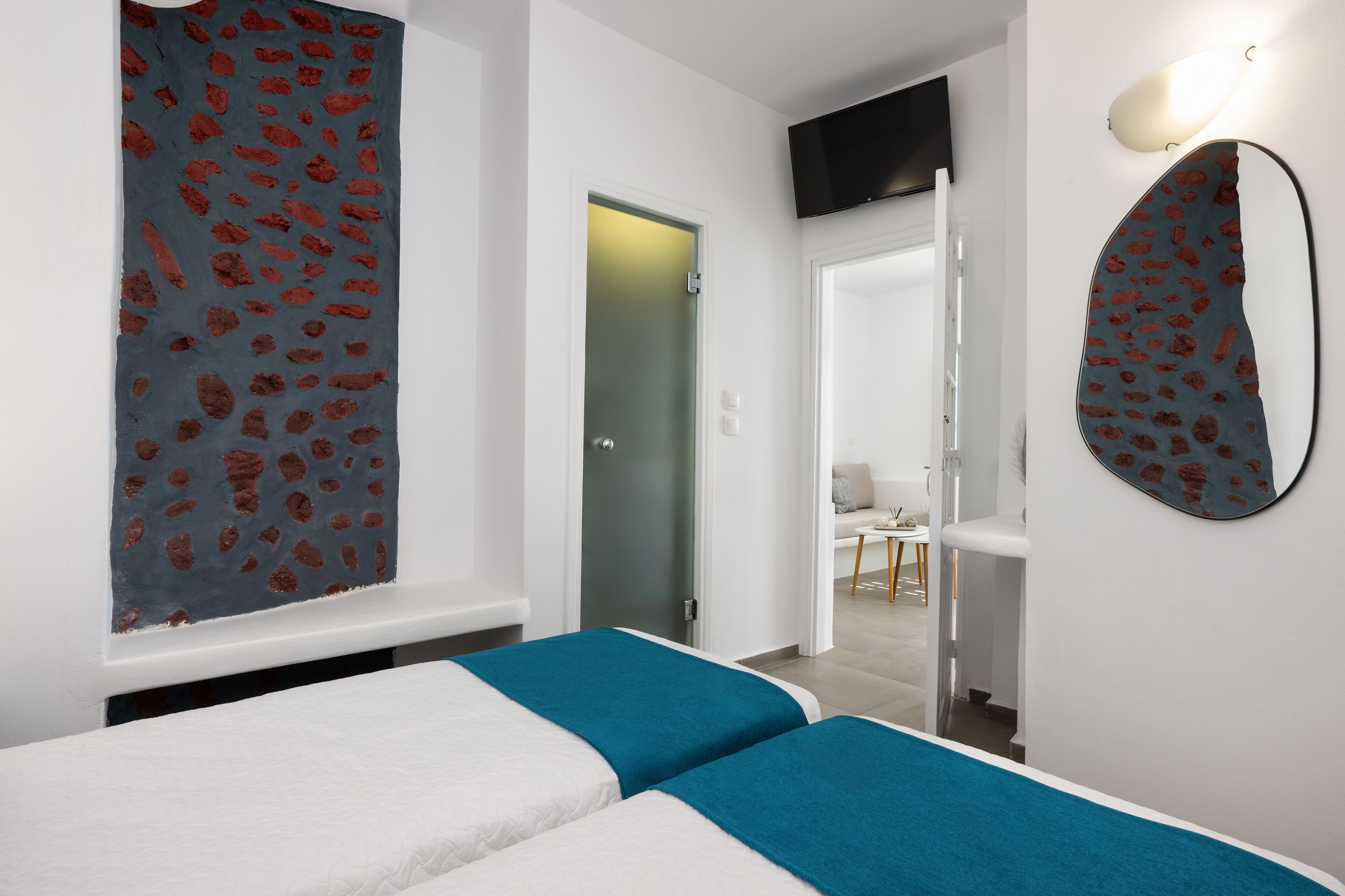 Une chambre d’hôtel avec deux lits, une grande fenêtre offrant une belle vue, un téléviseur à écran plat fixé au mur et un miroir au design original.