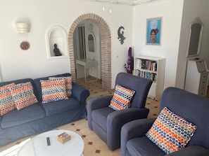 A living room with a blue sofa set, a round coffee table, and a bookshelf. - Rabat 6 - El Oasis de Capistrano! (Nerja)
