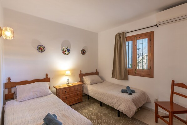 A bedroom with two beds, a wooden dresser, a nightstand with a lamp, and a window with curtains. - Tanger 3 - El Oasis de Capistrano! (Nerja)