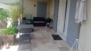 A covered patio area with a table and chairs, a grill, and a broom.