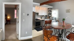 A modern kitchen with white cabinets, stainless steel appliances, and a dining area with a round table and leather chairs.