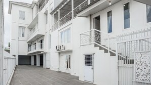 Un edificio de varios pisos con balcones, entrada protegida por un portón y un patio con azulejos.
