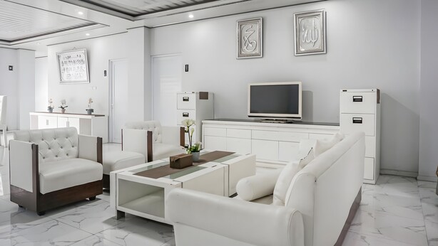 Una sala de estar moderna con muebles blancos, un televisor de pantalla plana y caligrafía decorativa en las paredes.