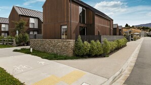 Un bâtiment moderne avec une base en pierre et un revêtement en bois, doté d’une grande entrée et d’une piste cyclable.