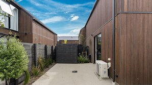 Un bâtiment moderne avec un chemin en béton menant à une entrée fermée par un portail.