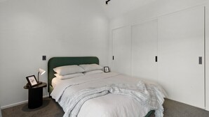 Une chambre à coucher avec un lit, une table de chevet avec une lampe, un tableau encadré et une armoire.