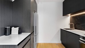 Une cuisine moderne avec des meubles de couleur sombre, un plan de travail blanc et un pare-feu en marbre.