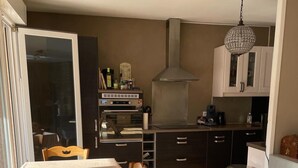 A compact kitchen with a dining table, a trash bin, and a chandelier. - SEVRIER, Bel appartement de 73M2 de 2 chambres pour 4 personnes avec parking et terrasse avec vue sur les montagnes, situé à 500m de la piste cyclable et du lac... (Sévrier)