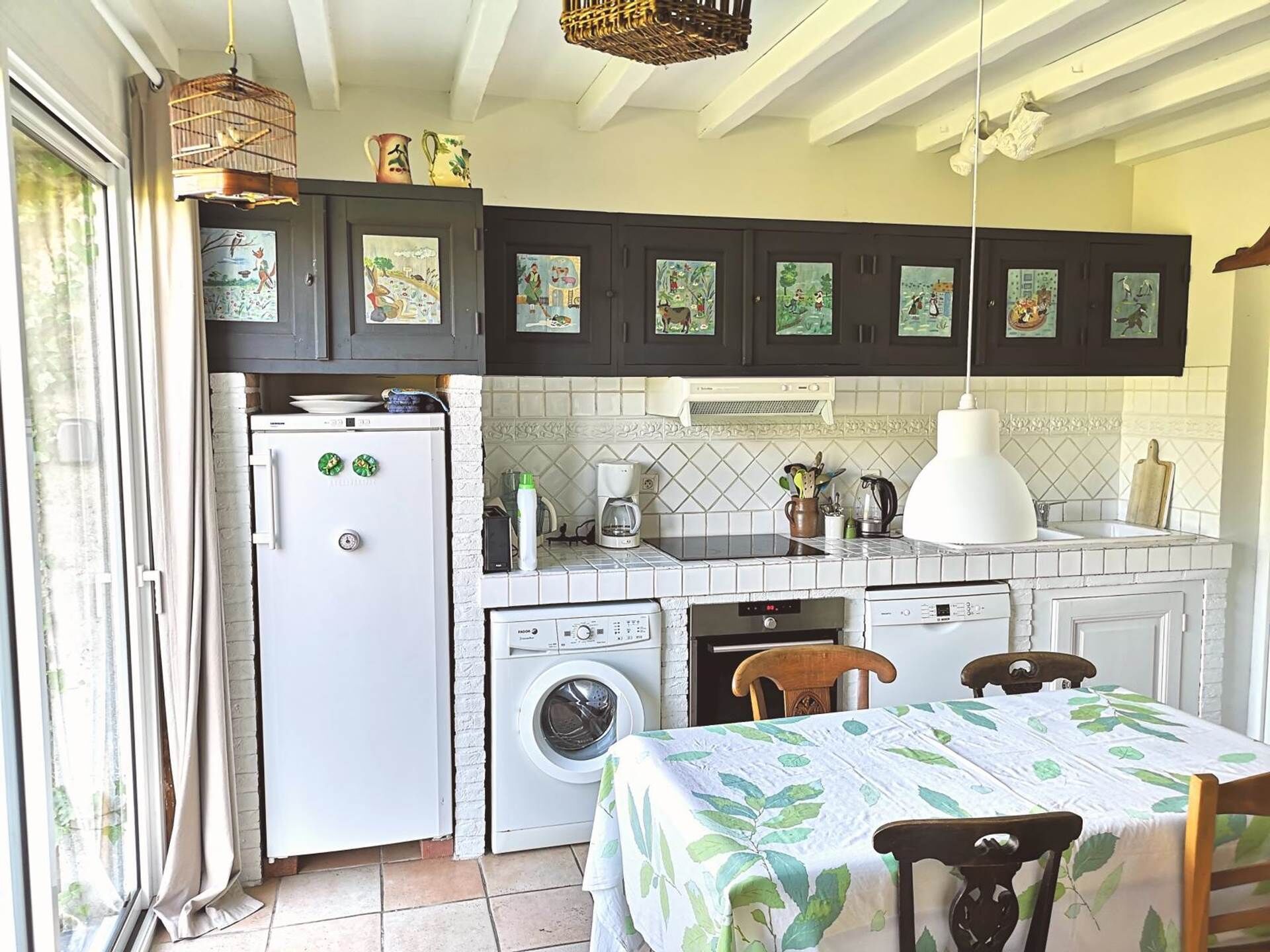Cocina compacta con lavadora, refrigerador, lavaplatos y comedor con mesa y sillas.
