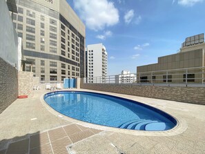 A rooftop swimming pool with a view of surrounding buildings.