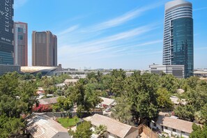 A cityscape with modern buildings, a prominent curved skyscraper, and residential areas with trees.