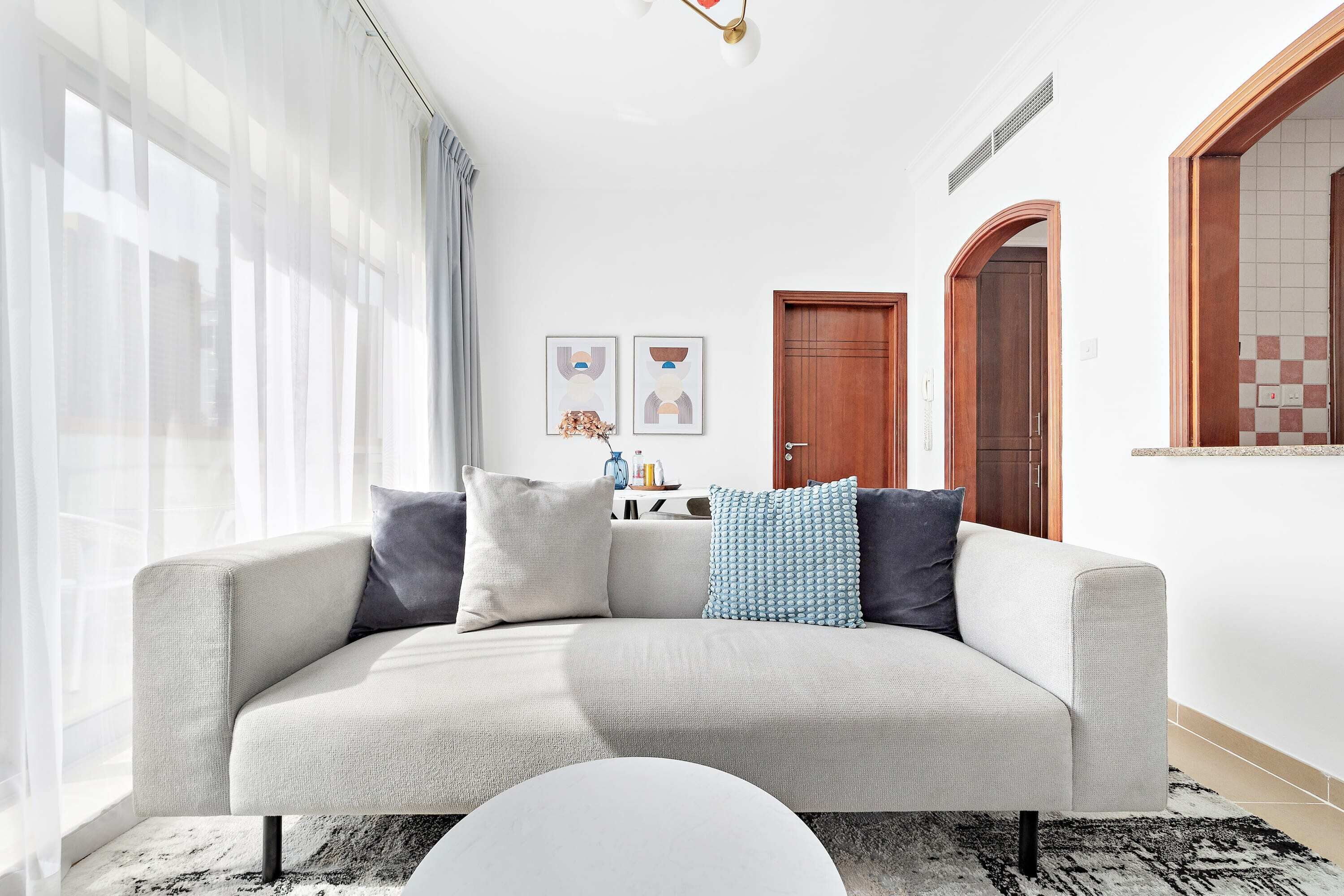 Una sala de estar moderna con un sofá, una mesa de centro y un comedor al fondo.