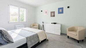 Quarto com uma cama, uma cadeira, uma escrivaninha e um radiador.