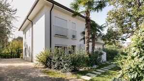 Uma casa moderna com fachada branca, uma palmeira e um jardim bem cuidado com um caminho de pedra.
