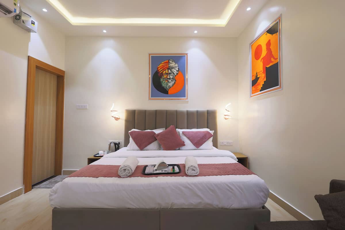Une chambre d’hôtel avec un lit, des oreillers, un plateau avec des serviettes et des œuvres d’art accrochées aux murs.