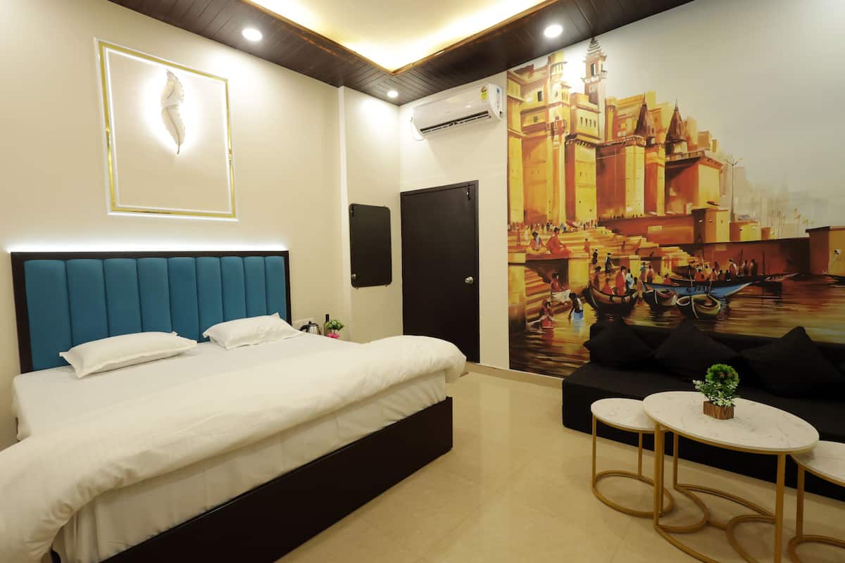 Une chambre d’hôtel avec un grand lit, un canapé, deux petites tables et une fresque représentant un paysage urbain.