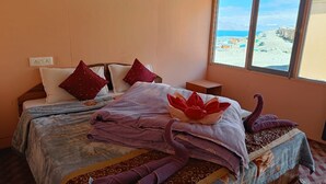Un llit ben arropat amb vista a la platja a través d'una finestra.