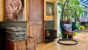 A cozy room with a large wooden door, a hanging chair with cushions, a wicker basket, and a radiator. - Hidden gem in Bayeux : 3 bedrooms, backyard and spa -  king and queen size beds (Bayeux)